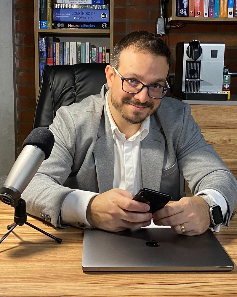 Consultório do Dr. Guilherme Loureiro Fracasso, com estante de livros e mesa de trabalho sob luz natural